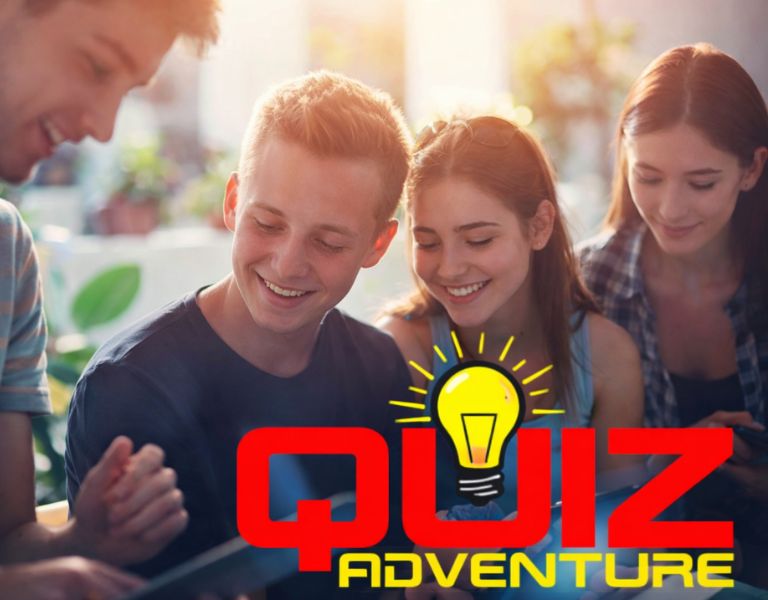 En gruppe unge sidder tæt sammen og smiler, mens de fokuseret kigger på en fælles opgave, formentlig på en tablet eller telefon. Stemningen er afslappet og positiv, og billedet signalerer samarbejde, idéudveksling og fælles engagement.